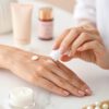 a-clean--minimalist-still-life-scene-featuring-a-w woman’s hand softly applying a small amount of white cream onto her fingers