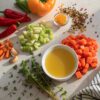 instant-soup raw ingredients often used in soup, such as colorful diced vegetables (carrots, celery, bell peppers) and dried herbs, surrounding a small, simple bowl of freshly prepared soup