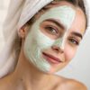 natural-purifying-mask close-up shot of a woman's hand gently applying a smooth layer of light green mint-colored clay mask to her cheek
